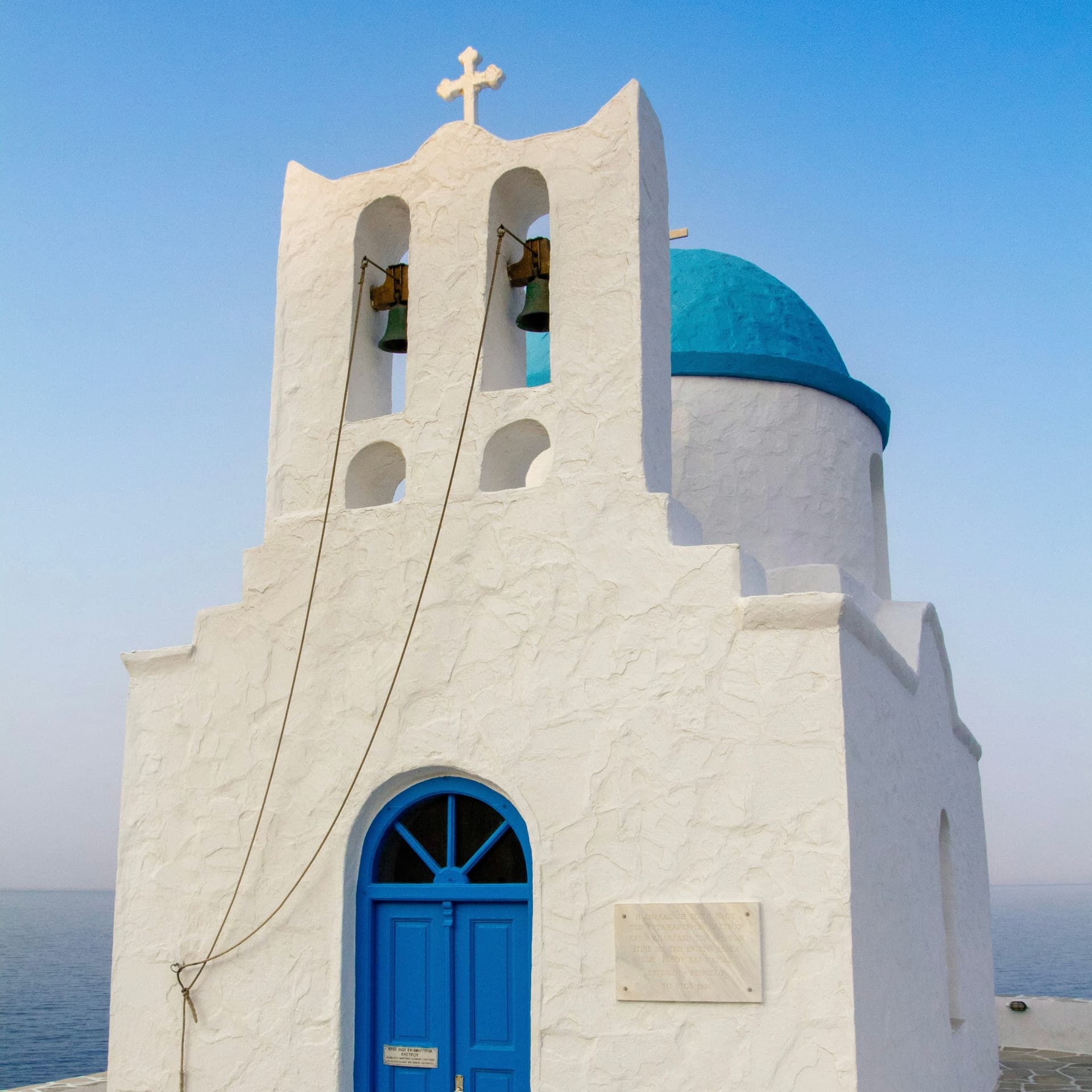 A whitewashed chapel with blue doors and dome on Sifnos