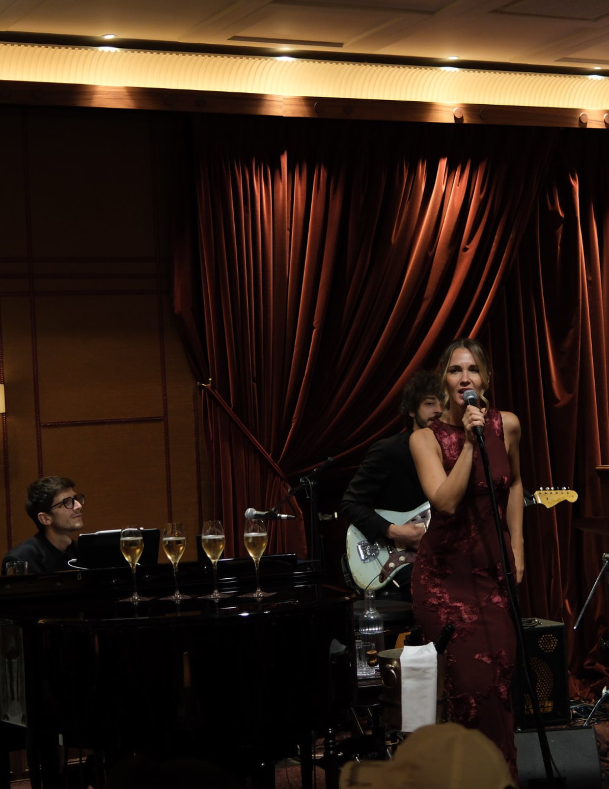 A singer and her band performing live under velvet curtains at Le Bar Américain, Hôtel de Paris Monte-Carlo