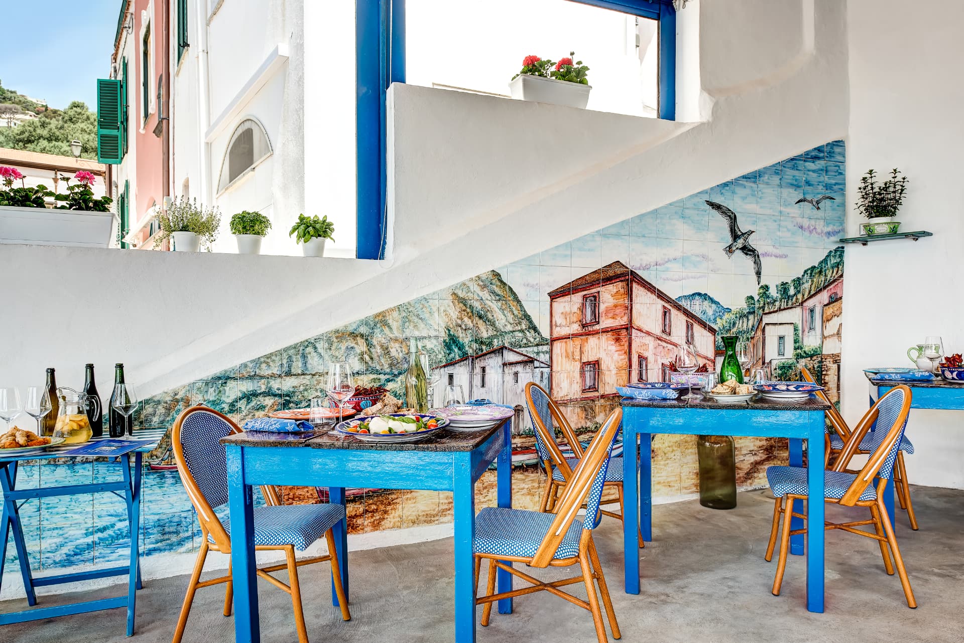 Blue tables and a hand-painted tile mural at Maria Grazia