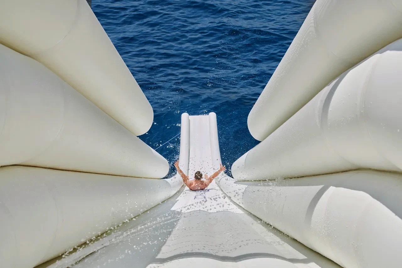 A guest riding Coral Ocean's inflatable slide down into the deep blue sea