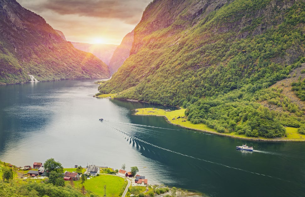 A boat crossing the narrow Nærøyfjord between green mountains