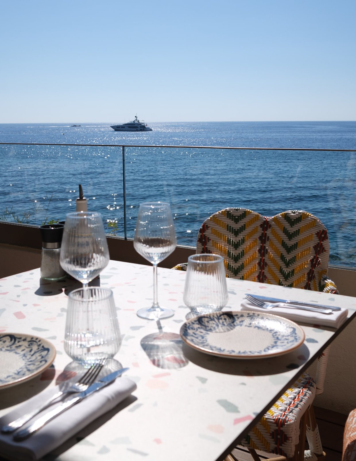A table set on La Pinède's terrace at Cap-d'Ail, with a yacht out at sea