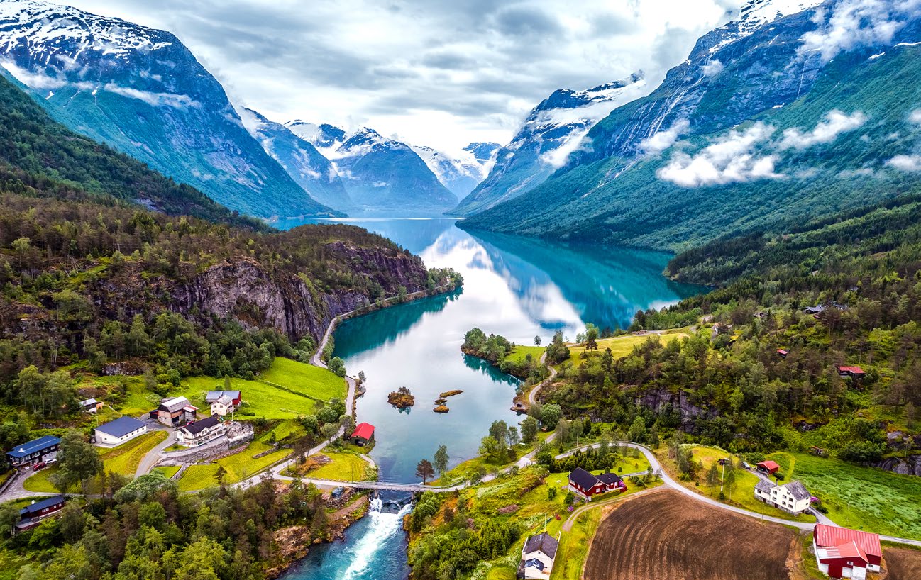 A green Norwegian fjord valley with mountains mirrored in still water