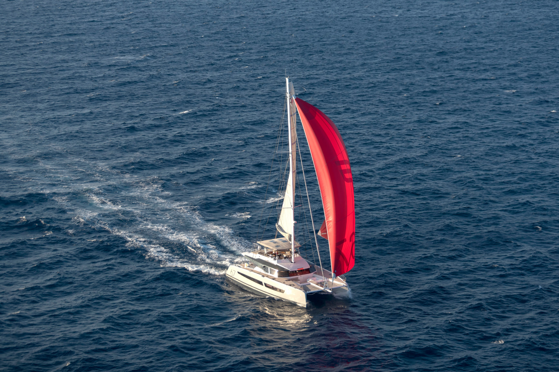 Floramye sailing under a red gennaker seen from the air