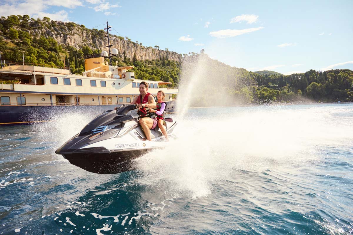 Guests on a jet ski beside Seagull II at anchor