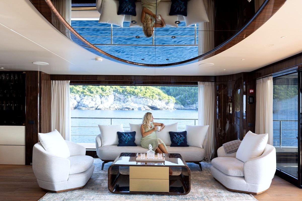 A guest relaxing in Enjoy's main saloon, with a wide window onto a Croatian cove