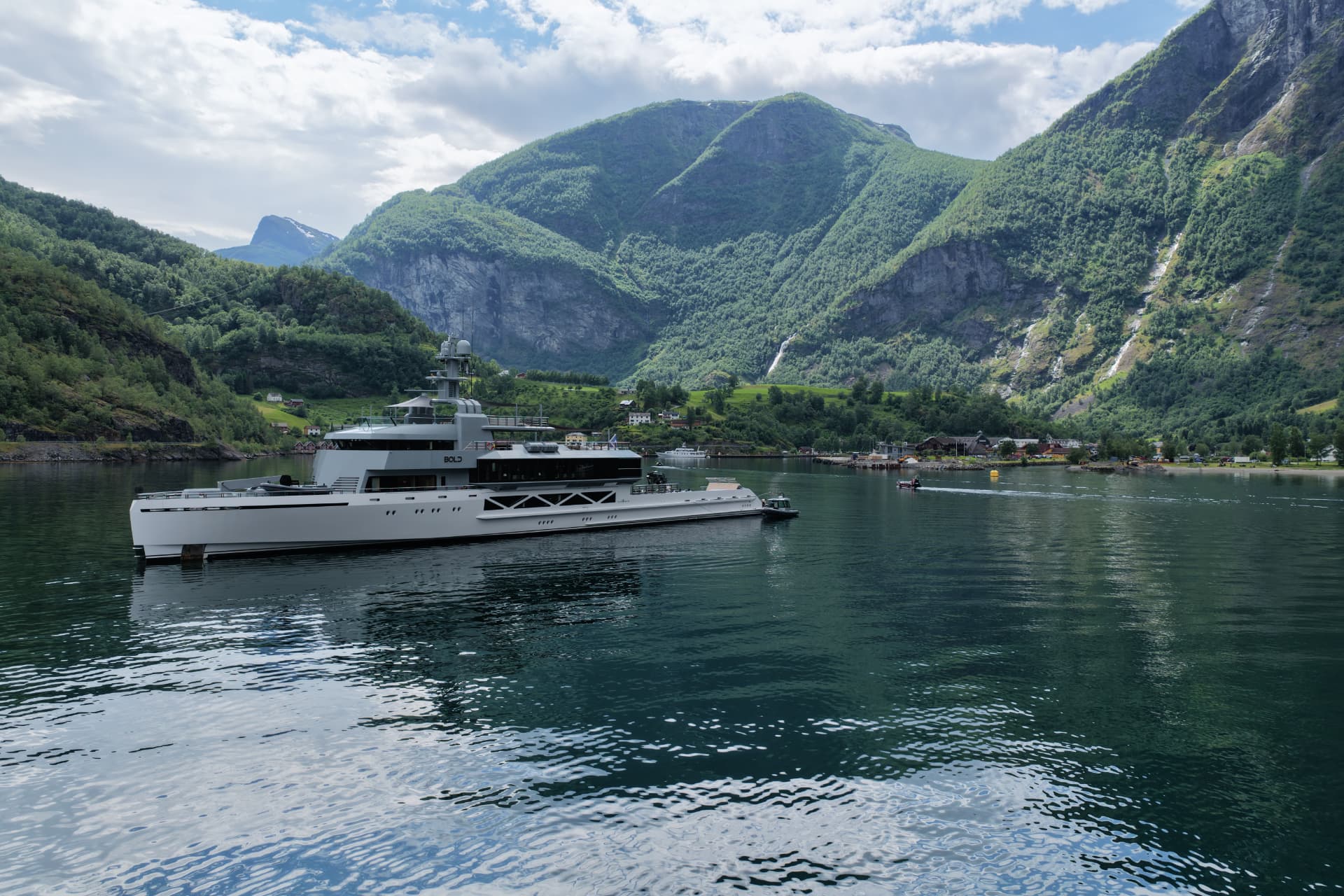 The explorer yacht Bold anchored in a Norwegian fjord beneath green mountains