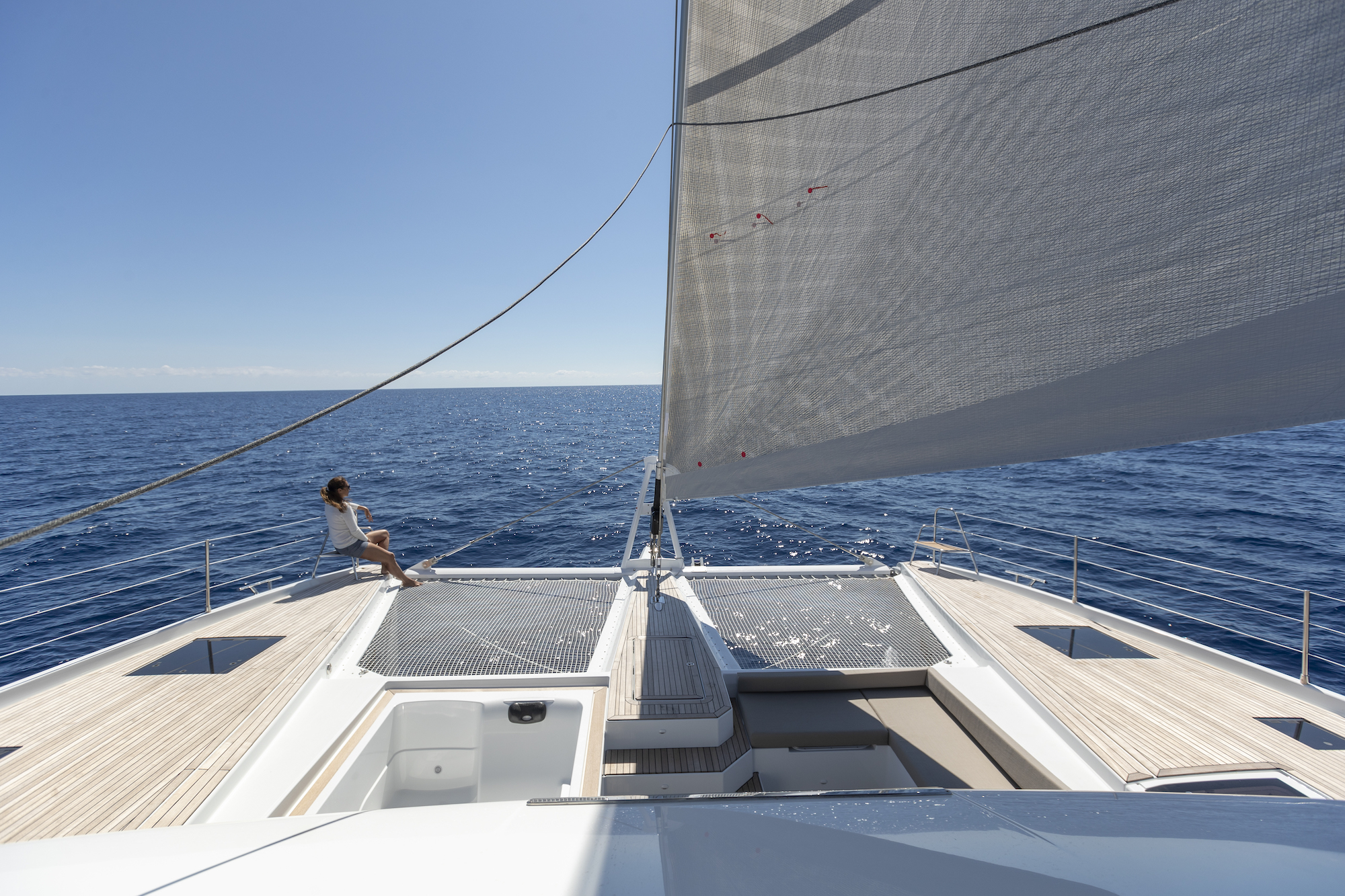 Guest relaxing on Floramye's foredeck trampolines under sail